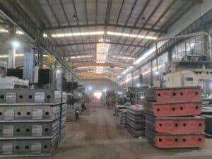 Stacks of heavy-duty steel chase plates and molds in a die cutting machine manufacturing facility, waiting for assembly or quality check.