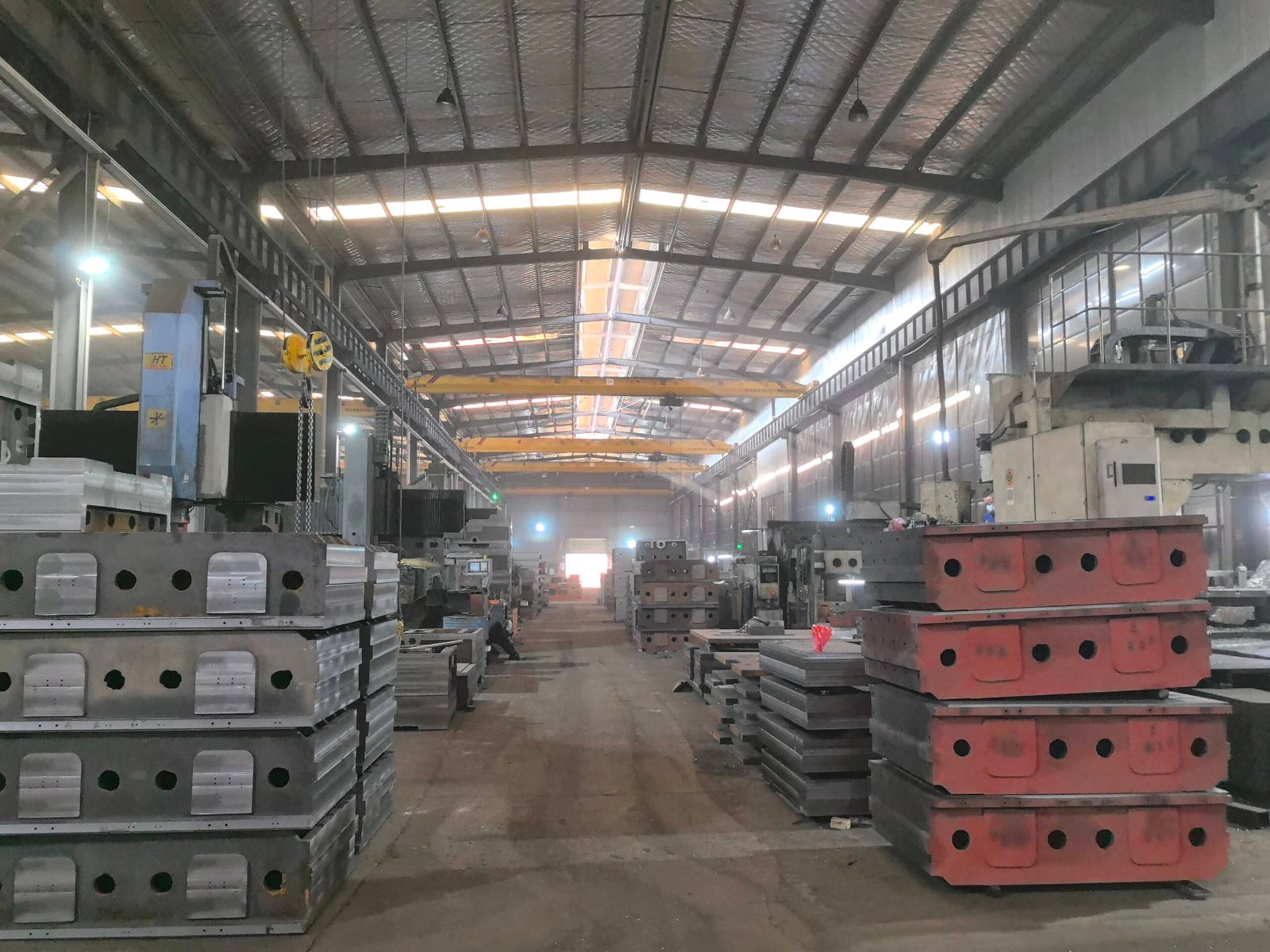 Stacks of heavy-duty steel chase plates and molds in a die cutting machine manufacturing facility, waiting for assembly or quality check.