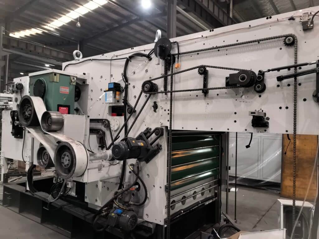 Close-up view of the drive system including chains, gears, and motors inside an automatic die cutter, critical for maintaining even cutting pressure.