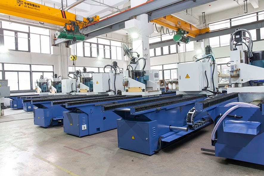 A row of identical blue CNC knife grinding machines in a factory, illustrating a high-volume production environment and the benefits of automated, repeatable sharpening processes.