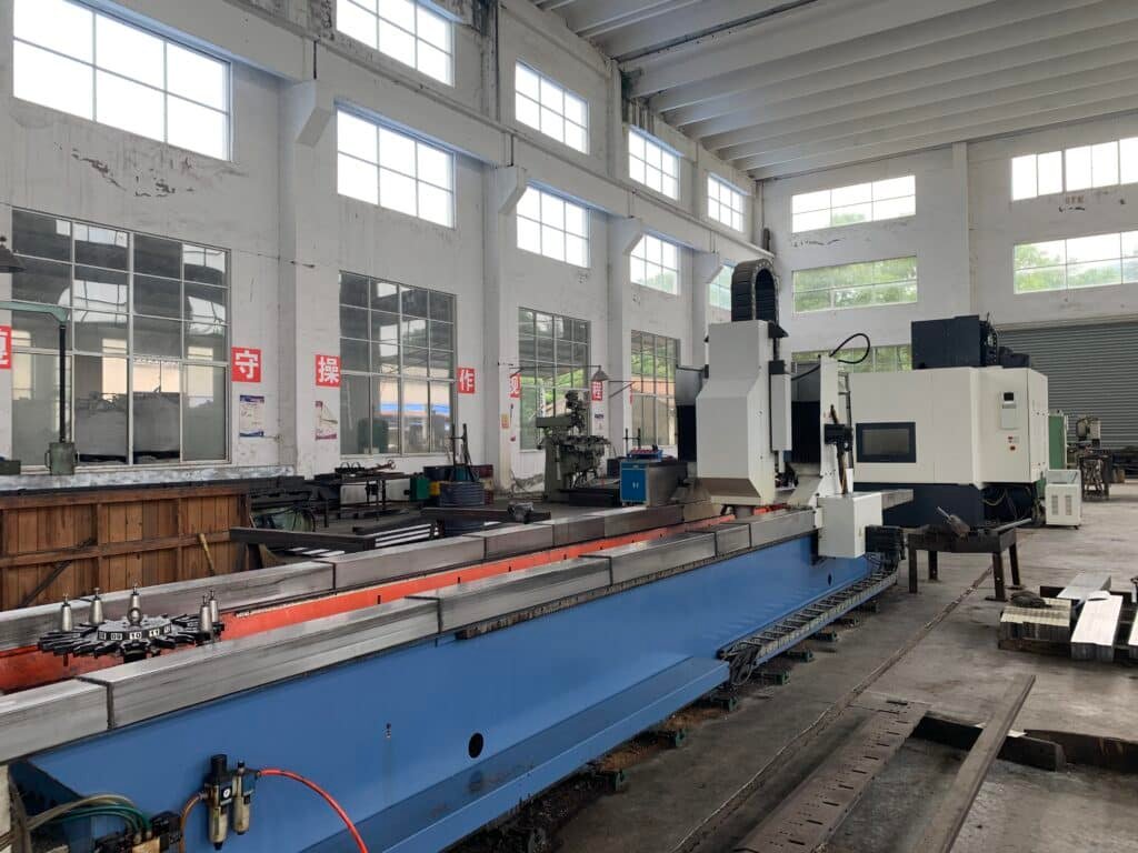 A long-bed CNC knife grinding machine in a manufacturing facility, highlighting its capability to handle large and long industrial blades.