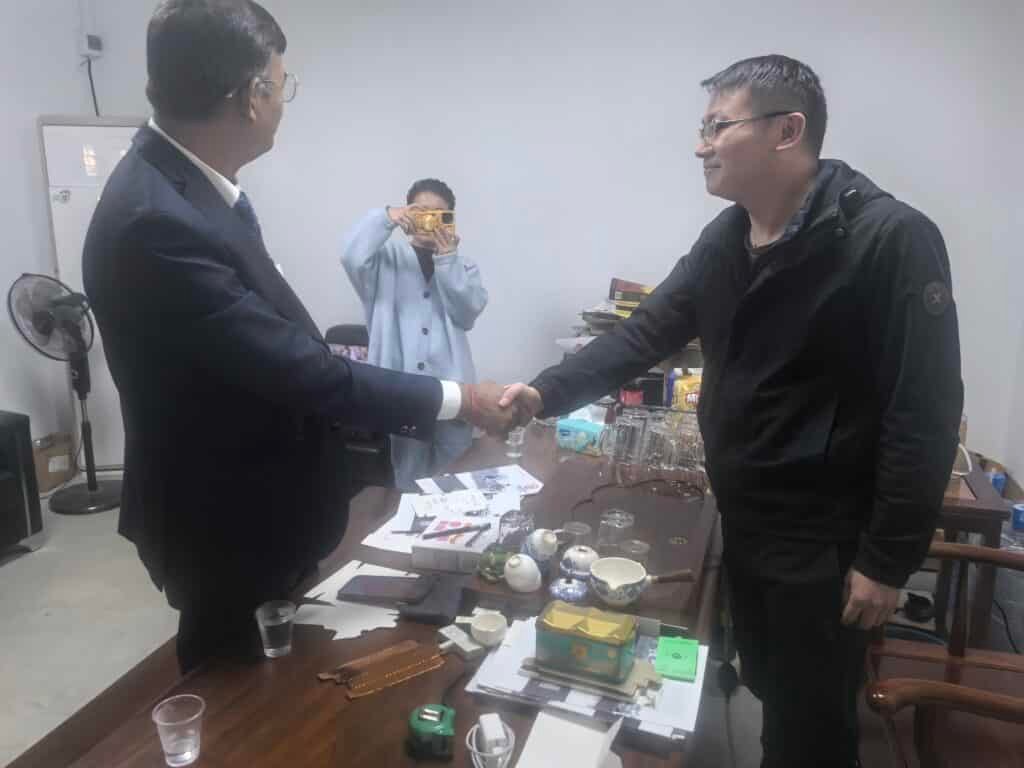Two business professionals shaking hands over a deal for industrial paper cutting machines, symbolizing partnership in the printing and packaging industry.