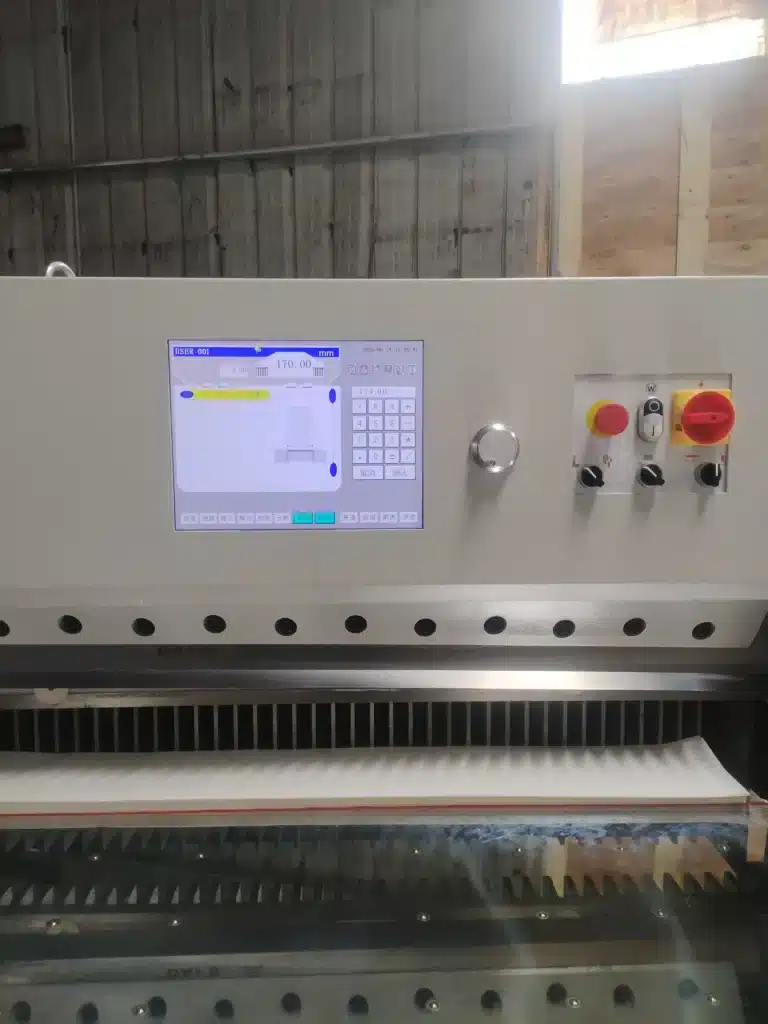 Close-up of paper cutting machine control panel with touchscreen interface and safety buttons for automation programming