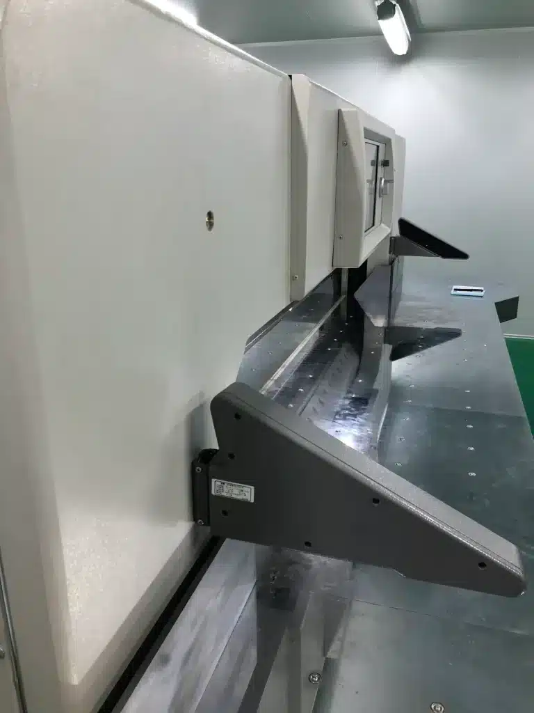 Close-up of photoelectric safety sensors and protective guards on paper cutting machine.