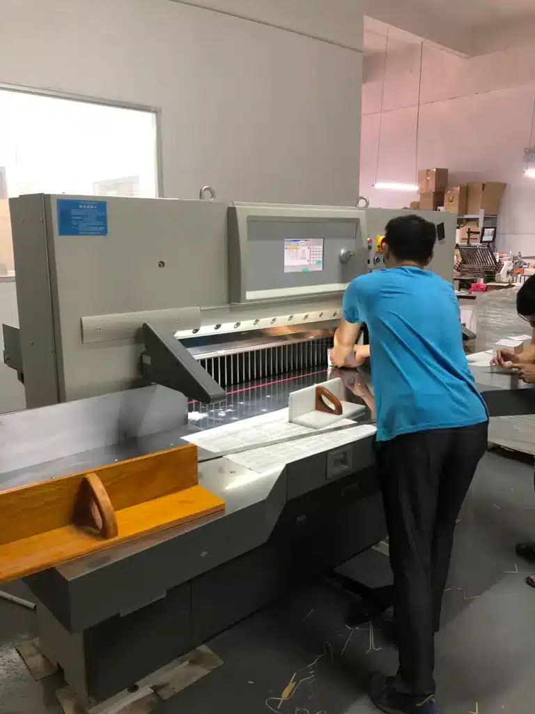 Operator conducting pre-operation check and inspecting safety guards before starting the paper cutter.