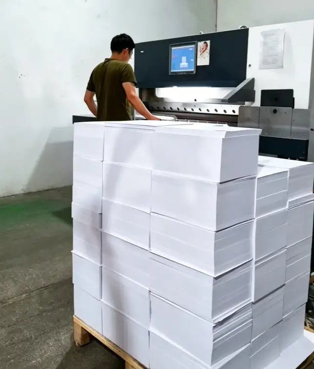 Operator jogging paper stack before cutting to prevent uneven cuts on a paper cutting machine