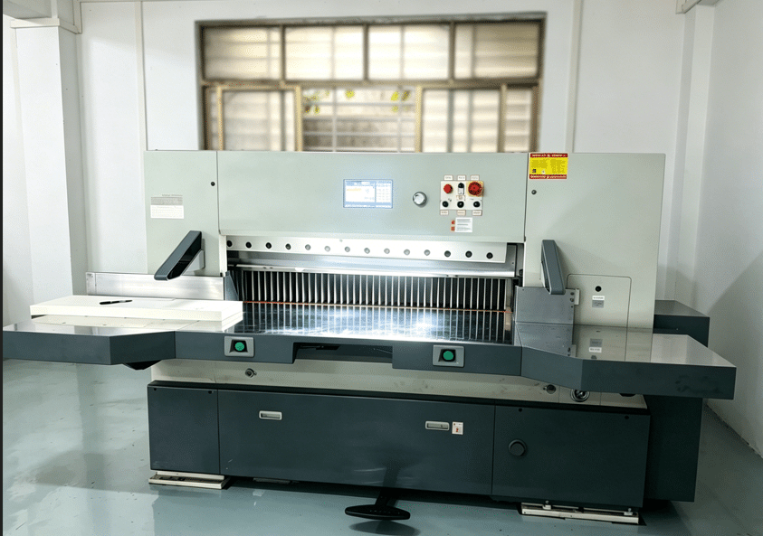Front view of high-speed paper cutter showing control panel, safety guards, and cutting area for precision calibration