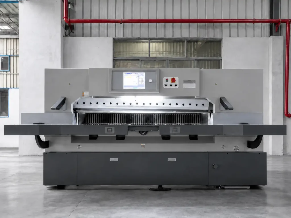 Front view of a heavy-duty industrial hydraulic paper cutting machine showing robust frame and wide cutting bed