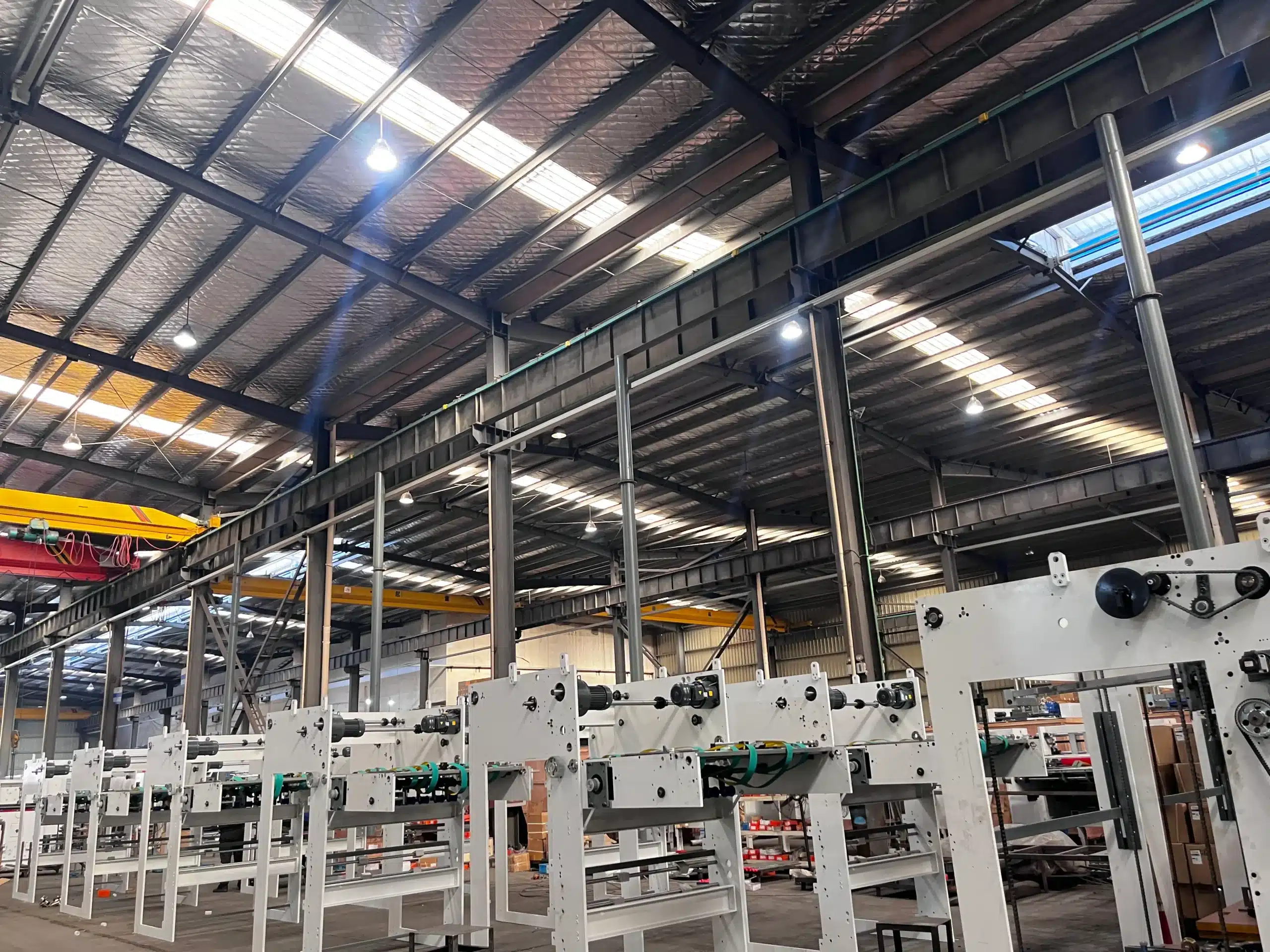 Wide-angle view of a modern die cutting workshop with multiple machine frames and overhead cranes.