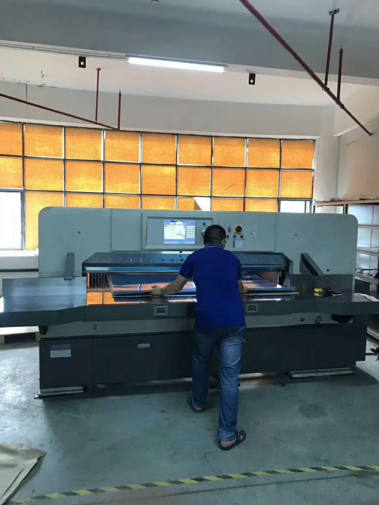 Rear view of operator working with high-speed paper cutter demonstrating process control and machine stability
