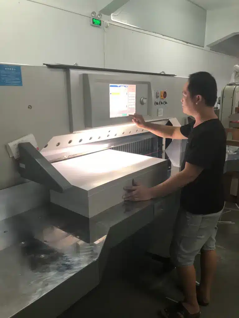 Operator using push sticks and proper material handling techniques during paper cutting operation.