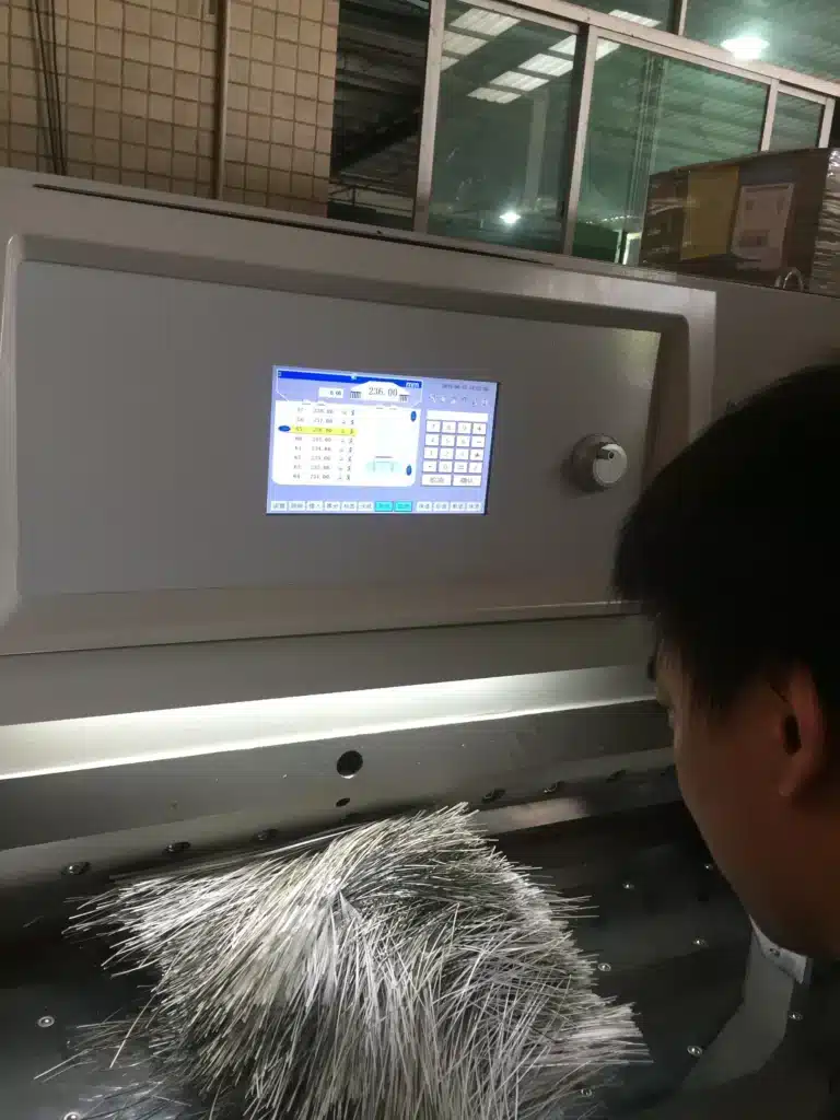 Operator controlling automatic knife grinding machine for precise industrial blade sharpening