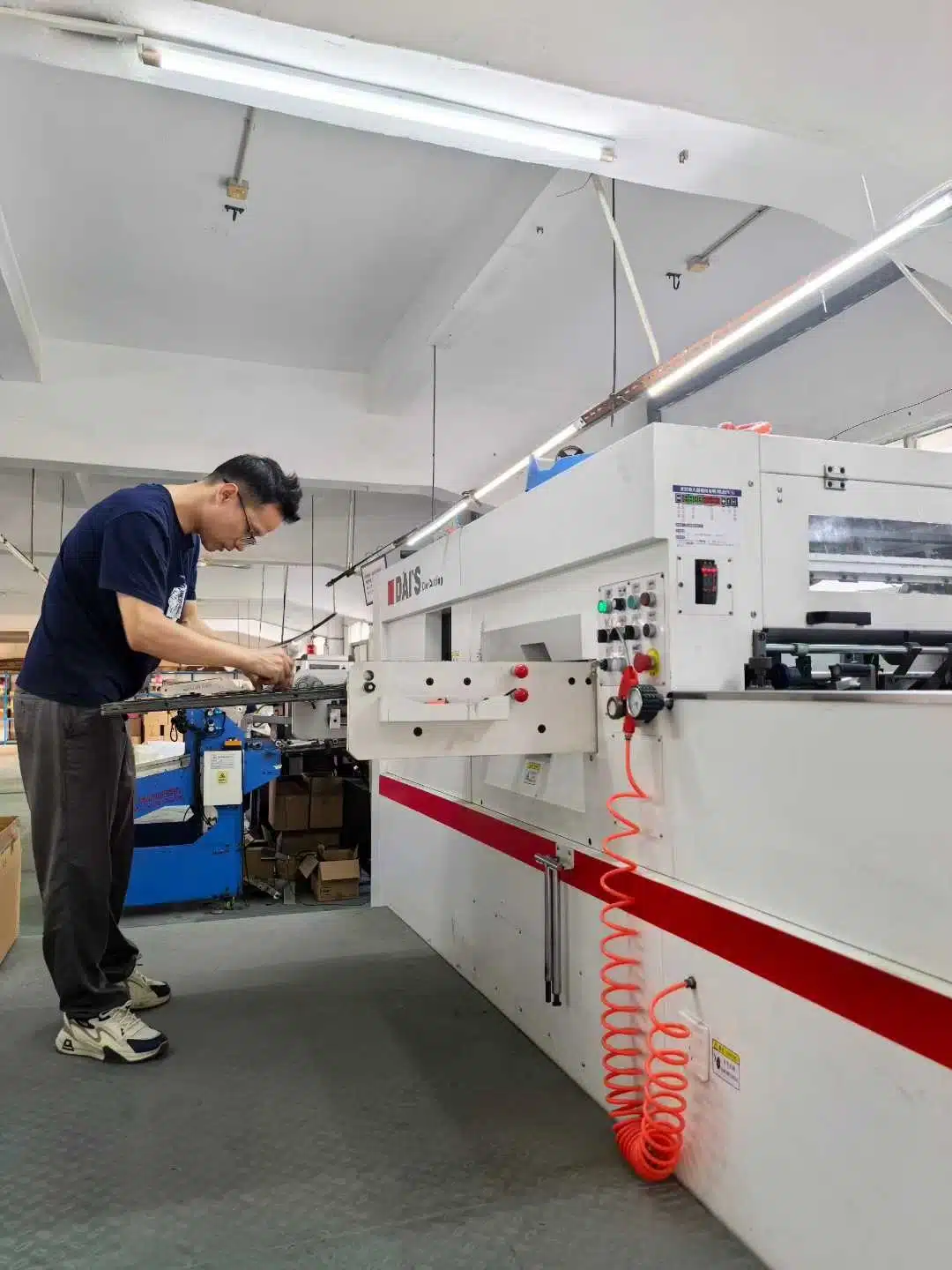 Technician assembling and testing the D1060S automatic die cutting machine in the workshop