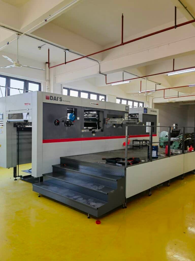 Packaging manufacturer upgrading to or operating an automatic die cutting machine with waste stripping unit, showing integrated workflow from die cutting to clean blank delivery