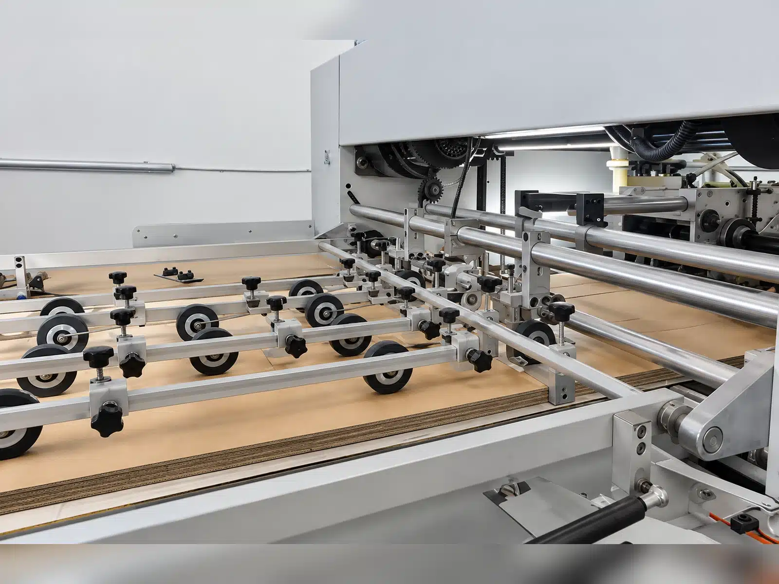 DAIS D1060 semi-automatic die cutting machine feeding and registration system with adjustable rollers and sheet guides for stable paperboard feeding.